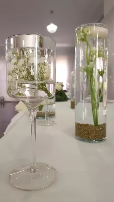 Centres de table classiques avec gypsophile et petites fleurs blanches flottantes dans des vases en verre, pour un mariage.