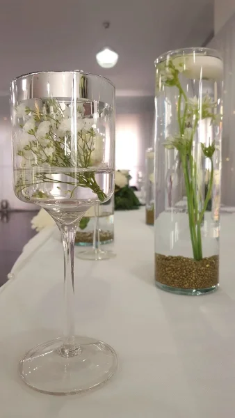 Centres de table classiques avec gypsophile et petites fleurs blanches flottantes dans des vases en verre, pour un mariage.