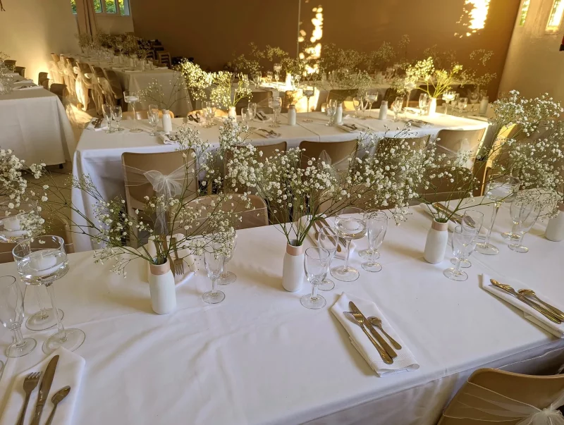 Minimalist country-style table centrepiece with white Gypsophila in cylindrical vases for a summer wedding.