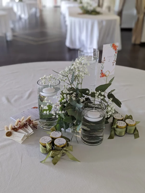 Table centrepiece with gypsophila, eucalyptus and floating candles in glass vases, country style.