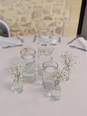 Centre de table de mariage bohème minimaliste avec gypsophile délicat dans de petits vases variés.