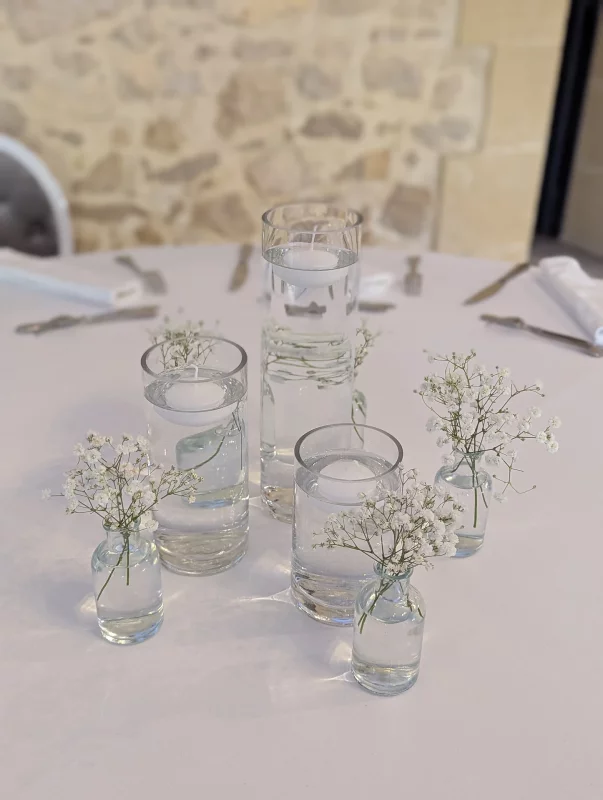 Centre de table de mariage bohème minimaliste avec gypsophile délicat dans de petits vases variés.