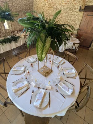 Grand centre de table exotique sur pied doré avec un assemblage luxuriant de feuilles de monstera et palmiers.