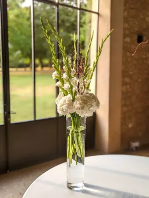 Centre de table élégant pour table d'honneur avec hortensias blancs, glaïeuls verts et branchages séchés, style champêtre classique.