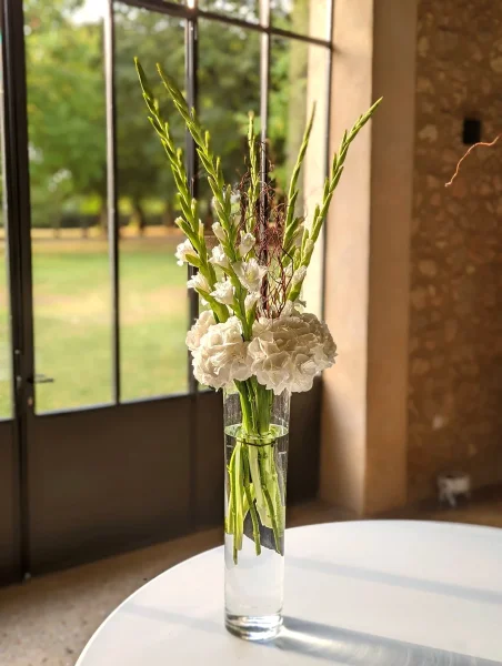 Centre de table élégant pour table d'honneur avec hortensias blancs, glaïeuls verts et branchages séchés, style champêtre classique.