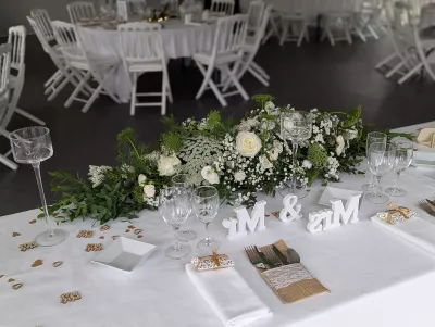 Long centre de table d'honneur champêtre avec roses, gypsophile et feuillage vert, pour mariage.