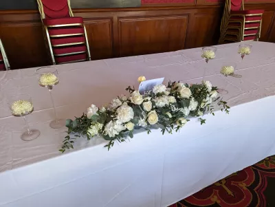 Long centre de table d'honneur classique avec roses blanches, œillets et gypsophile pour un mariage.