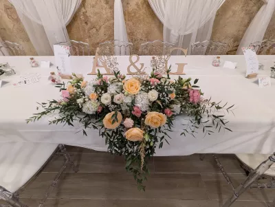 Centre de table d'honneur champêtre avec roses pêche, hortensias blancs et feuillage pour le mariage de Aurelie au Grand Moueys.
