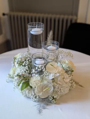 Sophisticated country-style table centrepiece with hydrangeas, anthuriums, and floating candles for a wedding.