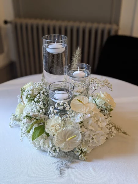 Sophisticated country-style table centrepiece with hydrangeas, anthuriums, and floating candles for a wedding.