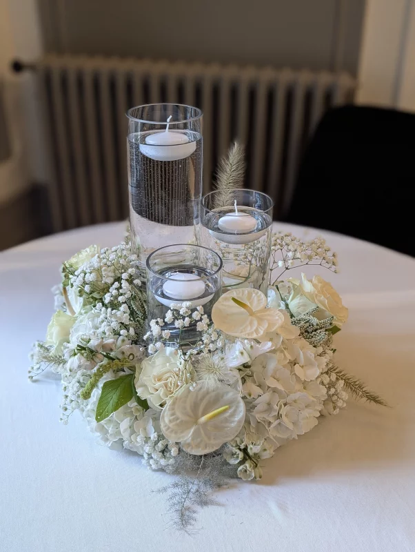 Sophisticated country-style table centrepiece with hydrangeas, anthuriums, and floating candles for a wedding.