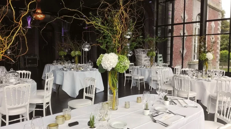 Centre de table mariage classique et moderne avec hortensias blancs et verts, branches décoratives, verrerie élégante.