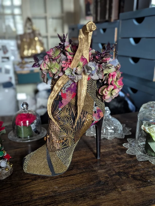 Centre de table mariage classique avec hortensias roses et verts, feuillage pailleté et une chaussure décorée dorée, pour un mariage