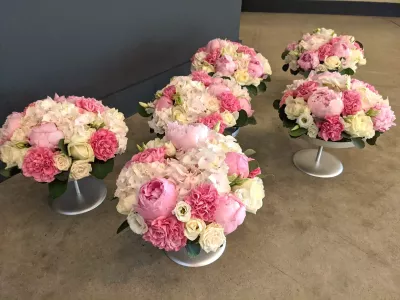 Centres de table classiques avec hortensias, pivoines et roses dans des tons blancs et roses pour un mariage estival.