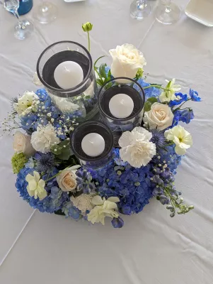 Magnifique centre de table floral bohème pour mariage avec hortensias bleus, roses crémeuses et chardons.