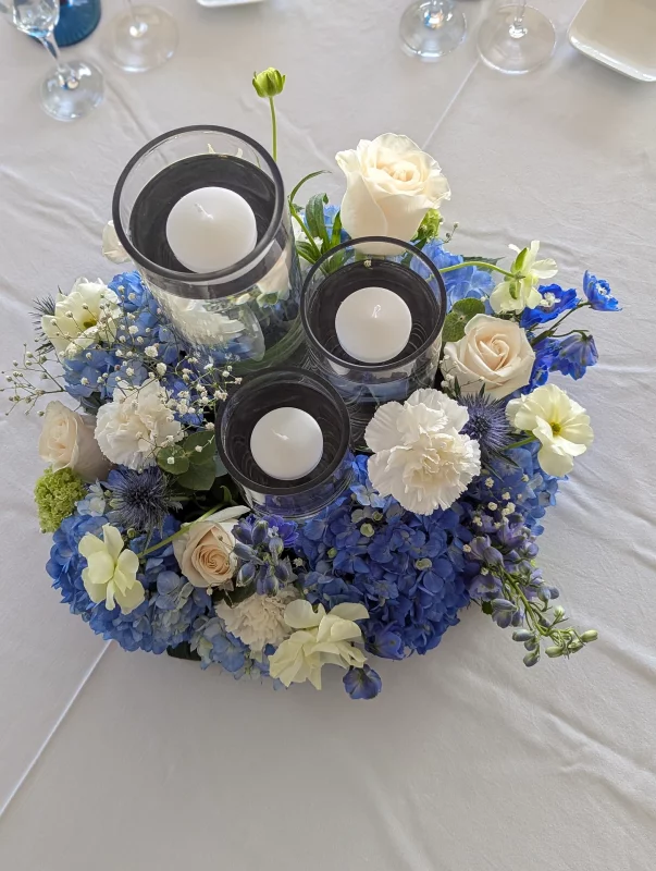 Stunning bohemian floral table centrepiece for a wedding, featuring blue hydrangeas, creamy roses and thistles.
