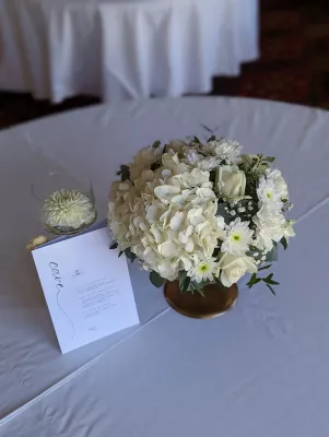 Centre de table rond classique avec hortensias, roses blanches et chrysanthèmes, pour une réception de mariage.
