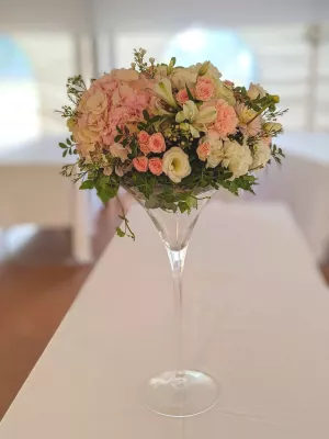 Grand centre de table classique avec hortensias roses, roses pâles, lisianthus et alstroemerias blancs dans un vase martini.