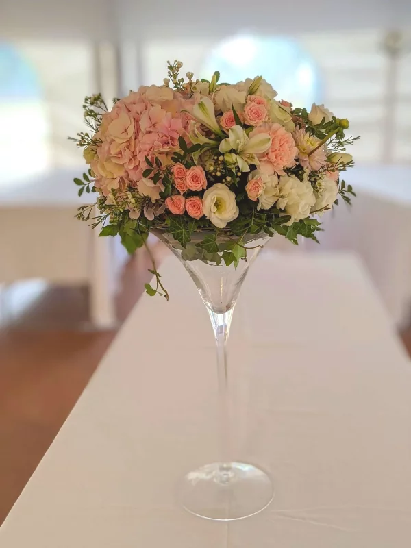Grand centre de table classique avec hortensias roses, roses pâles, lisianthus et alstroemerias blancs dans un vase martini.