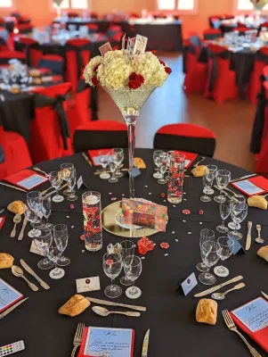 Composition florale de centre de table classique avec hortensias blancs, roses rouges, et cartes à jouer pour mariage élégant.