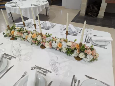 Centre de table long et fleuri avec hydrangeas, roses et carnations dans les tons pastel pour un mariage.