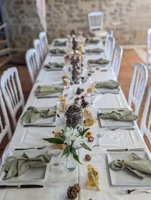 Sophisticated rustic table centrepiece with white lilies, green foliage, and natural elements for the wedding.