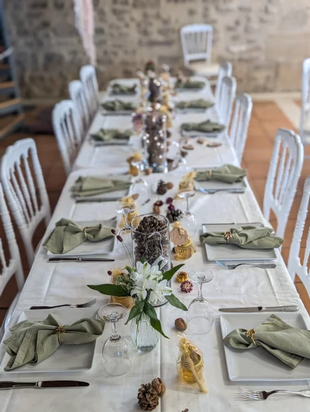 Sophisticated rustic table centrepiece with white lilies, green foliage, and natural elements for the wedding.