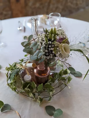 Centre de table champêtre avec lisianthus blancs et violets, gypsophile et lierre, dans des contenants variés.