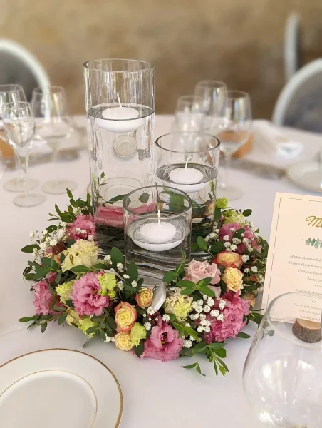 Centre de table champêtre avec lisianthus roses et verts, mini-roses crème, gypsophila et eucalyptus, bougies flottantes.