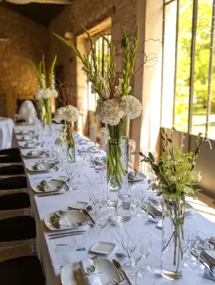 Rangée de centres de table pour table d'honneur, hortensias blancs, glaïeuls verts, branchages secs, ambiance champêtre.