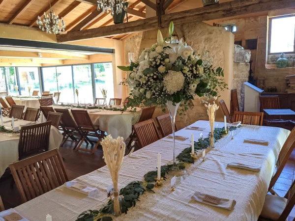 Grand centre de table de mariage bohème avec lys, hortensias, roses et eucalyptus dans un vase haut. Ambiance chic.