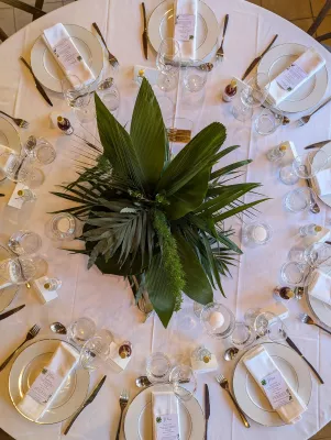 Centre de table rond exotique avec un arrangement dense de grandes feuilles tropicales et de fougères vertes.