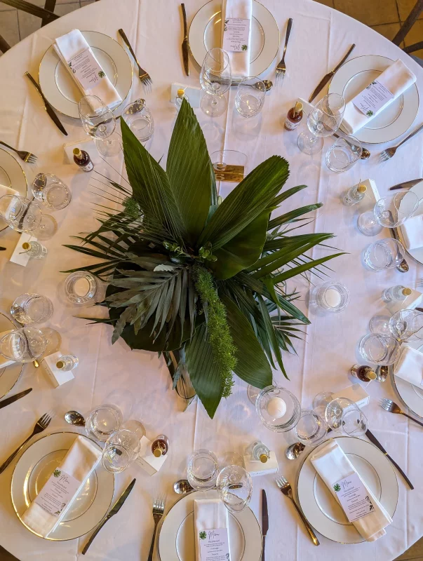Centre de table rond exotique avec un arrangement dense de grandes feuilles tropicales et de fougères vertes.