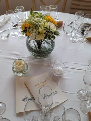 Centre de table champêtre avec œillets blancs, alstroemerias jaunes et feuillage, agrémentant une table de mariage.