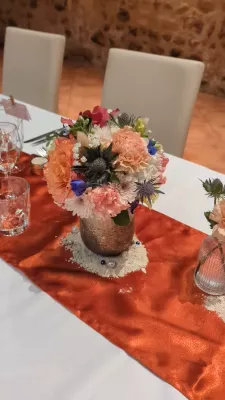 Sophisticated rustic table centrepiece with pink carnations, peach roses, and blue thistles for wedding.
