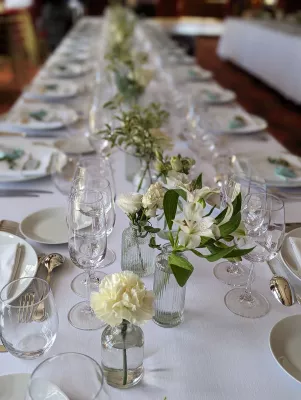 Centres de table de mariage minimalistes avec œillet blanc, rose et alstroemeria dans de petits vases pour un dîner élégant.