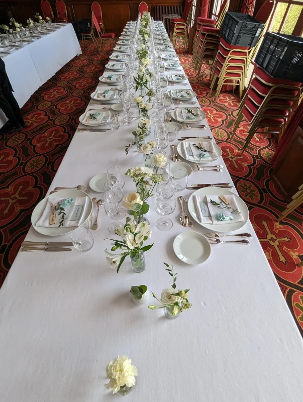 Minimalist wedding tablescape featuring small arrangements of white flowers and greenery for the reception in Pessac.