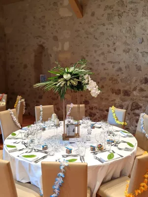 Centre de table exotique pour mariage de Girard, avec orchidées, anthuriums et feuillages tropicaux sur colonnes dorées à Pessec.