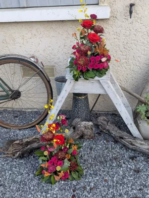 Composition florale pour centre de table de mariage, avec roses rouges, dahlias, orchidées oncidium et feuillage.