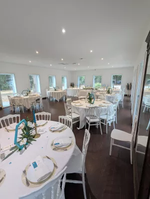 Round table centrepieces with white orchids, green foliage, and blue candles for a sophisticated country wedding.