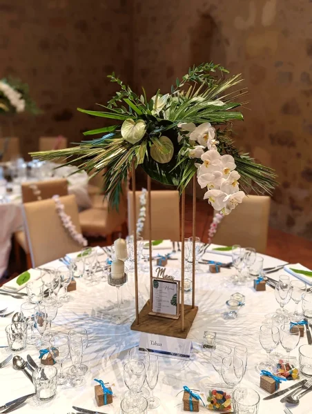 Composition de centre de table exotique avec orchidées phalaenopsis, monstera et anthuriums pour mariage.