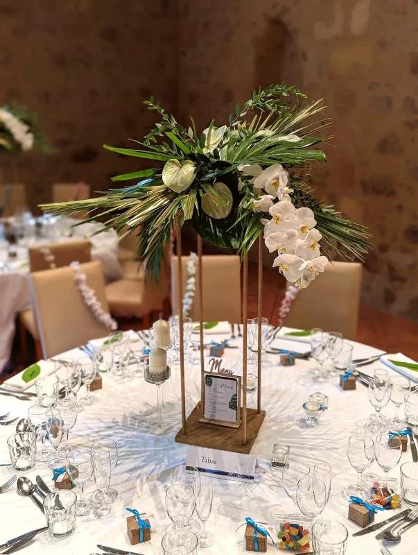 Composition de centre de table exotique avec orchidées phalaenopsis, monstera et anthuriums pour mariage.