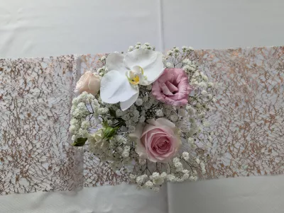 Centre de table de mariage classique avec orchidées blanches, roses roses pâles et gypsophile délicat.
