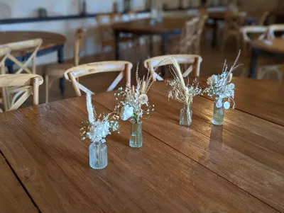 Centres de table bohèmes avec pampa, fleurs séchées blanches dans des mini-vases pour le mariage d'Elsa.