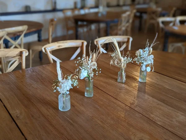 Centres de table bohèmes avec pampa, fleurs séchées blanches dans des mini-vases pour le mariage d'Elsa.