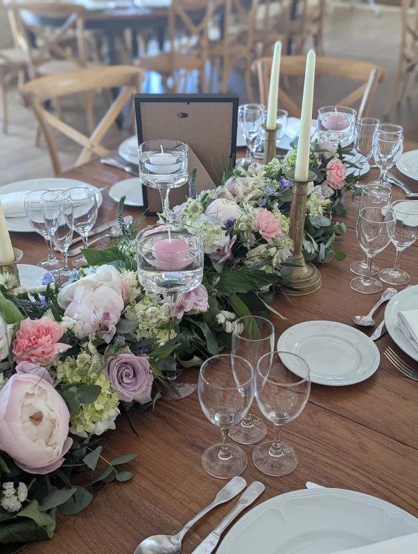 Garden-style head table centrepiece with pink peonies, roses, pale green hydrangeas and eucalyptus