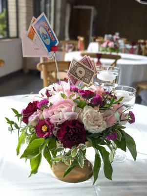 Centre de table romantique organique avec pivoines, roses et cartes Monopoly pour mariage.