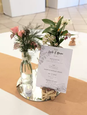 Centre de table champêtre sophistiqué avec roses, alstroemerias et feuillage dans des bouteilles recyclées.