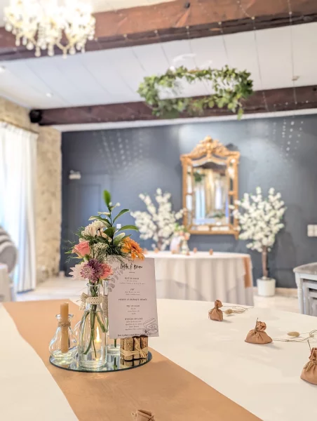 Centre de table champêtre sophistiqué avec roses, alstroemerias et feuillage dans des bouteilles recyclées.
