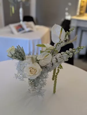 Sophisticated country-style table centrepiece with white roses, anthuriums, and gypsophila for a wedding.